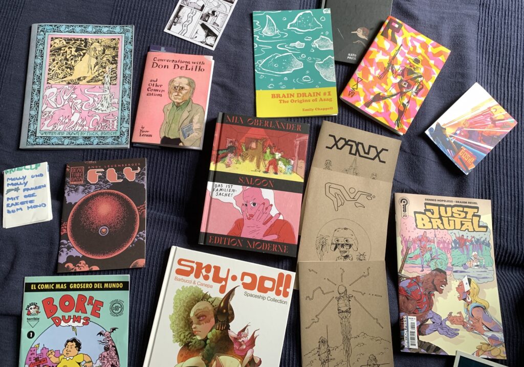 many comic books and zines laid out on a blanket
